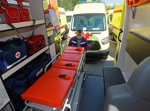 Фельдшер выкатывает каталку из машины скорой