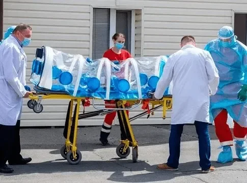 Два фельдшера переносят инвалида в кресле